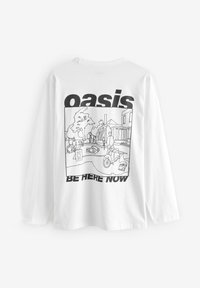 Balta ilgomis rankovėmis marškinėliai su juoda grafine iliustracija, vaizduojančia gatvės sceną, kurioje ryškiai išspausdintas tekstas "oasis BE HERE NOW".