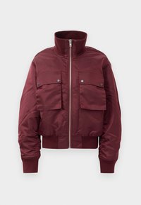 Burgundy bomber jacket with high ribbed collar, front zipper, two large flap pockets with snap buttons, and ribbed cuffs and hem.