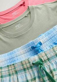Deux t-shirts de taille moyenne pliés, un rose et un vert clair, accompagnés de deux shorts à taille élastique à motifs, dans des tons bleus et verts.
