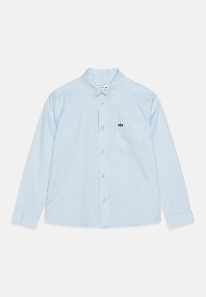 Chemise bleu clair à manches longues avec col boutonné et poche poitrine ornée d’un petit logo crocodile vert.