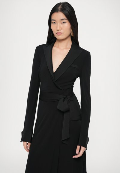 Μαύρο φόρεμα wrap με μακριά μανίκια, διαθέτει βαθύ V-λαιμόκοψη, λεπτομέρεια δεσίματος στη μέση και διακριτική τσέπη. Λείο ύφασμα με κομψό σχεδιασμό.