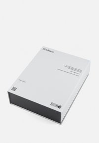 Boîte rectangulaire blanche avec une base noire, présentant un texte minimaliste et des logos sur le couvercle. Comprend un code QR et des détails de marque.