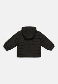 Veste matelassée noire avec manches longues et capuche attachée, vue de dos sur fond blanc.