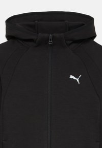Felpa nera con zip realizzata in materiale morbido, dotata di cappuccio, dettagli a coste sui lati e logo bianco Puma sul lato sinistro del petto.