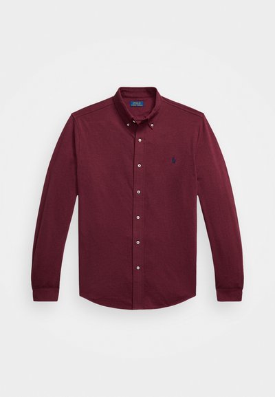 Langermet burgunder knappskjorte med krage, frontknapper og liten marineblå brodert logo på venstre bryst.