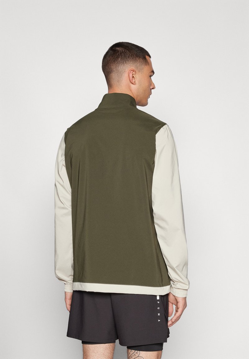 Lichte jas met een olijfgroene achterkant en een roomwitte voorkant, voorzien van lange mouwen en een hoge kraag. Inclusief elastische manchetten en zoom.