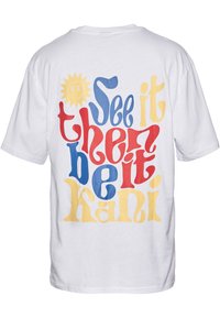 White cotton t-shirt featuring multicolored text on the back: “See it, then be it, Kani” in red, blue, and yellow with a sun graphic.