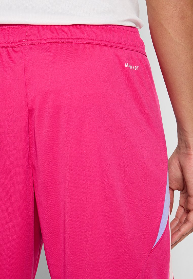 Shorts de sport roses avec une taille élastique, présentant une texture lisse et un accent violet clair sur le côté. La marque "AEROREADY" est visible.