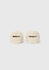 Krämfärgade tofflor med en mjuk, fluffig textur. Rundad design och öppen baksida, med en slät sula och minimala sömnadsdetaljer.