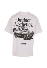 Camiseta blanca de algodón con un gráfico negro de una camioneta y texto que dice "Aestética al Aire Libre" en una fuente en negrita en la parte posterior.