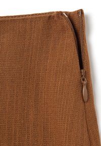 Braune, strukturierte Stofftasche mit einem sichtbaren Reißverschluss auf der rechten Seite. Das Material wirkt gewebt mit einer natürlichen, rustikalen Oberfläche.