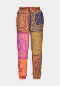 Joggers coloridos con un diseño que mezcla púrpura, naranja, marrón y azul, fabricados con una tela suave y con cintura y puños elásticos.