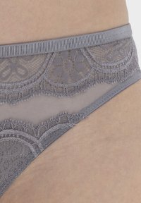 Tanga gris de encaje que presenta una base de malla suave, un intrincado borde de encaje con patrones florales y una suave cintura elástica.
