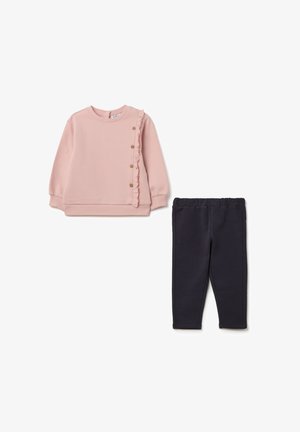 Roze sweatshirt met ruffle-detail en houten knopen, gecombineerd met donkerblauwe stretchleggingen. Beide gemaakt van zachte, comfortabele stof.