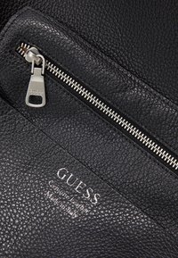 Borsa in pelle nera con superficie texturizzata, dotata di chiusura a zip in argento e logo del marchio impresso. Made in Italy.