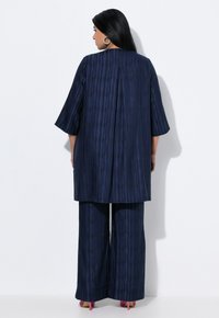 Marineblaue Tunika mit senkrechten Streifen, Dreiviertelärmeln und passenden weiten Hosen. Glatte Textur mit subtilen Musterdetails.