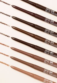 Åtta ögonbrynspennor arrangerade vertikalt, i varierande nyanser av brunt. Varje penna har en spetsig ände och en märkt bas för identifiering.