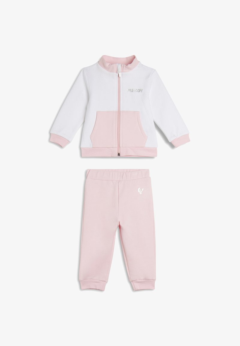 Chándal infantil blanco y rosa que incluye una chaqueta con cremallera y bolsillo frontal, y pantalones a juego con cintura elástica y detalle de logo.