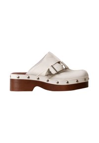 Sabot en cuir blanc avec semelle plateforme en bois marron, clous argentés le long de la semelle et une bride réglable avec boucle argentée.