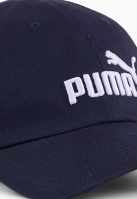 Granatowa czapka bejsbolowa z bawełny. Posiada haftowane białe logo „PUMA” oraz graficznego pumę. Zakrzywiony daszek i regulowany pasek z tyłu.