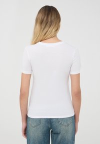 T-shirt bianco a maniche corte con scollo rotondo, realizzato in un tessuto morbido e leggero. Design minimalista, senza motivi o accessori visibili.