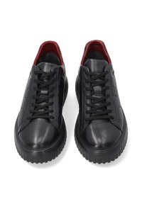 Zwarte leren sneakers met een gladde textuur, voorzien van zwarte veters en een contrasterende rode binnenvoering. Dikke rubberen zolen met gegroefde randen.