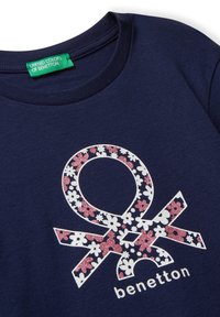 Dunkelblaues Rundhals-T-Shirt mit einem floralen Benetton-Logo in Weiß und pinkem Glitzer sowie einem grünen Markenlabel am Halsausschnitt.