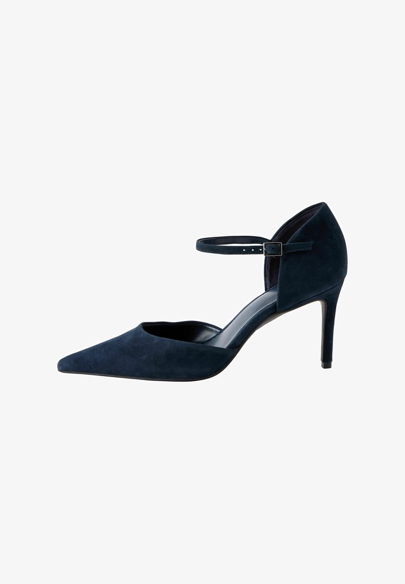 Escarpins en suede bleu marine à talon haut avec bout pointu et bride de cheville, présentant un design épuré et une texture douce.