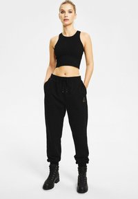 Czarny krótki top i dopasowane czarne spodnie dresowe z elastycznym pasem. Z drobnym logo, w zestawieniu z czarnymi botkami na sznurowadła.