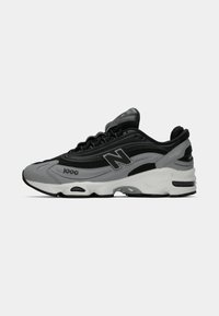 Black and grey New Balance 1000 sneaker with mesh and synthetic upper, white cushioned sole, and "N" logo on the side.