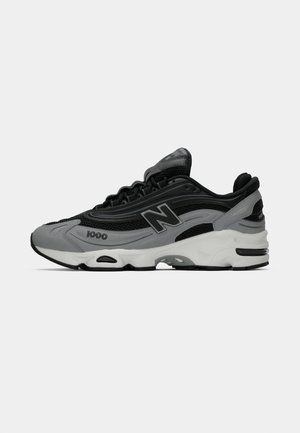 Sneaker New Balance 1000 noir et gris avec une tige en mesh et synthétique, semelle blanche avec rembourrage, et logo "N" sur le côté.