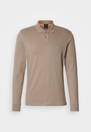 Polo a maniche lunghe in cotone beige chiaro con bottoni a tre e una piccola patch con logo sul petto. Presenta polsini a coste.