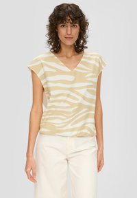 V-Ausschnitt-Bluse in hellem Beige mit weißen Zebramustern. Kurze �Ärmel und eine lässige Passform, aus einem leichten, strukturierten Stoff gefertigt.