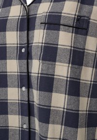 Marineblå og beige ternet skjorte med knaplukning og brystlomme, med sort piping og runde plastikknapper. Struktureret stof.