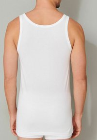 White cotton tank top with a round neckline and wide straps, shown from the back, highlighting its simple design and smooth texture.