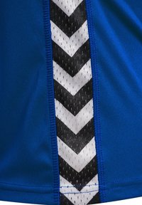 Blå atletisk skjorta med ett texturerat svart och vitt chevronmönster längs sidan, framhävd av en åtsittande design och elastisk väv.