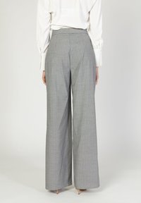 Pantaloni grigi a gamba larga con un sottile motivo a righe, vita alta e dettaglio plissettato. Tessuto leggero con una texture liscia.