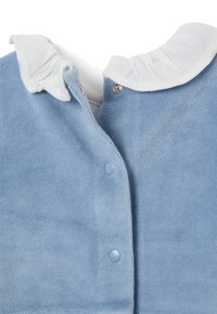 Vêtement en velours côtelé bleu clair avec un col blanc à volants. Doté de boutons-pression en plastique et d'une texture douce. Aucun motif ni accent supplémentaire.