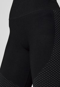 Leggings de deporte negros con una cinturilla texturizada, cuerpo suave y un degradado estampado en el lateral para un interés visual adicional.