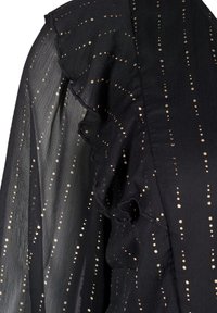 Svart genomskinlig blus med en texturerad yta, prydd med guldfärgade prickmönster och volangdetaljer längs halsringningen och ärmarna.