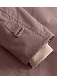 Leicht rosa wasserfeste Jacke mit glatter Textur, beige innerer Bündchen und einem bronzefarbenen Metallverschluss am Ärmel zur Anpassung.