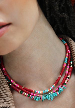 Multicolore Perlenkette mit roten, pinkfarbenen, türkisfarbenen und goldenen Akzenten. Enthält glatte und strukturierte Perlen, die in geschichteten Strängen angeordnet sind.