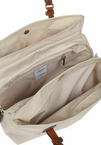 Borsa in tessuto beige con dettagli in pelle marrone. Presenta un interno spazioso con più scomparti, inclusa una tasca con zip e una chiusura a scatto.