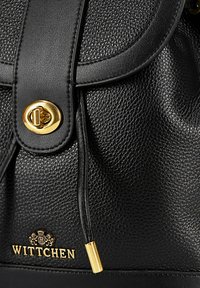 Sac à dos en cuir noir avec une surface texturée, fermeture en laiton doré et logo de la marque. Les accents comprennent un détail de fermeture à cordon.