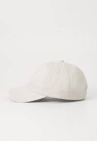 Beige színű baseball sapka ívelt karimával, hat paneles kivitelben, szellőzőlyukakkal. Finom varrással és puha tapintással rendelkezik.