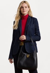 Bolsa de ombro em couro preto com uma textura suave, detalhes em hardware dourado e uma silhueta curva. Apresenta um mecanismo de fecho seguro.