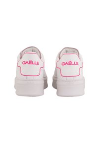 Sneakers bianchi con finitura in pelle liscia, dotate di un logo rosa sul tallone. Forma arrotondata e collare imbottito per il comfort.