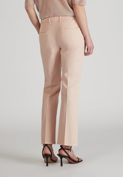 Pantalons rose clair avec une coupe droite, dotés de deux poches arrière et d'une taille plate. Portés avec des talons hauts noirs à lanières.