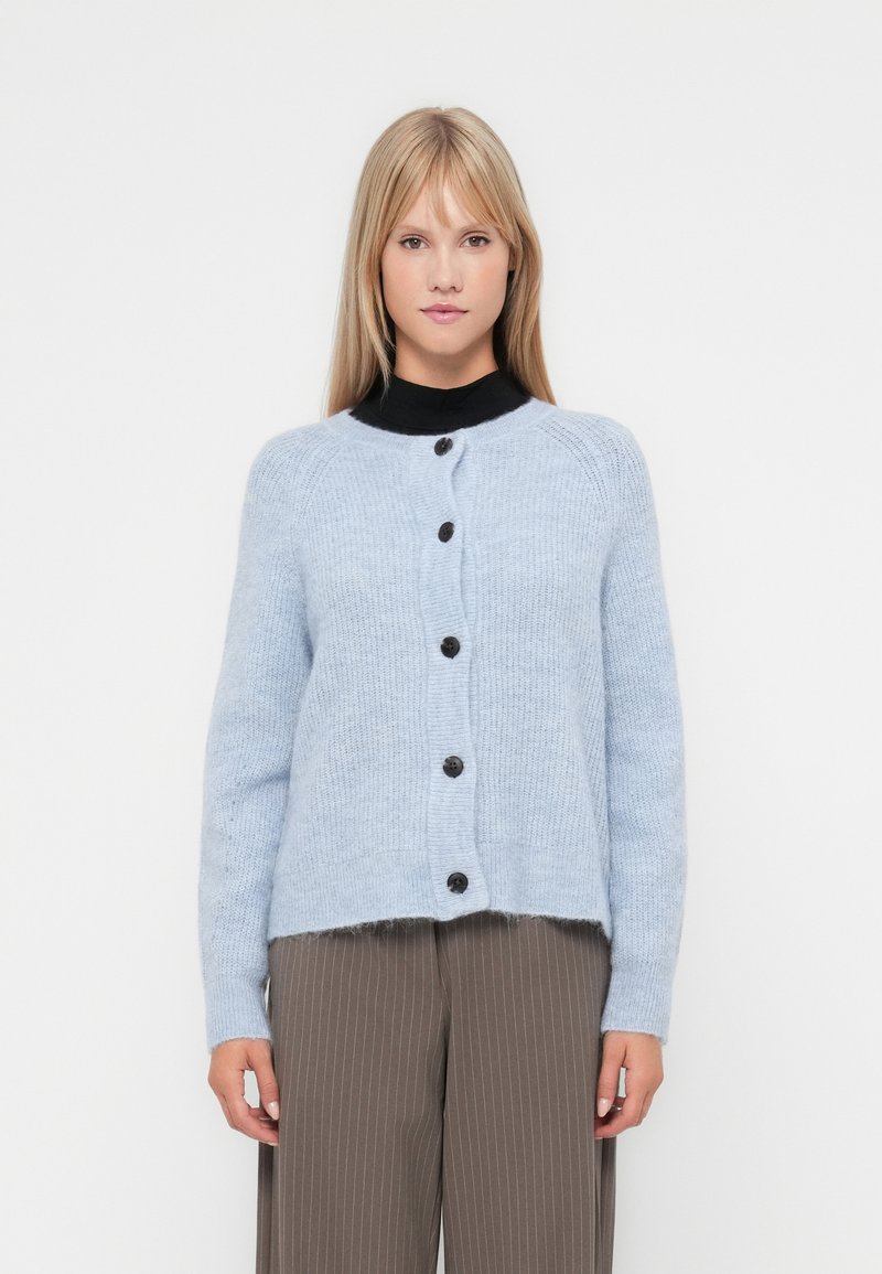 Gaiši zils kardigāns, kas izgatavots no mīksta auduma, ar apaļu dekoltē un sešām tumšām pogām priekšpusē, ar nedaudz īsāku apakšmalu.