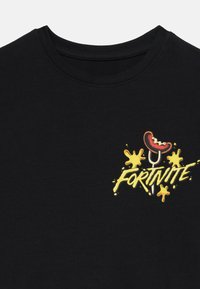 Juoda trumpomis rankovėmis marškinėliai, kuriuose pavaizduotas spalvingas karštas svogūnas ir žodis "FORTNITE" geltona spalva su purslų akcentais.